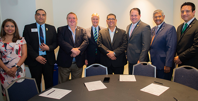 A group of Texas REALTORS® and representatives of the Mexican Association of Real Estate Professionals (AMPI) gather around a table before signing Memorandums of Understanding.