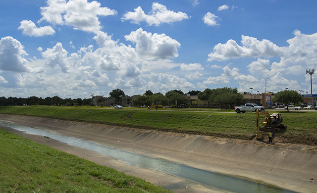 An excavator digs at the edge of Brays Bayou in Houston