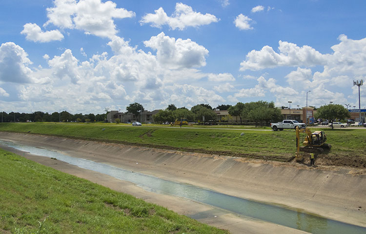 A lone excavator digs at the edge of Brays Bayou in Houston