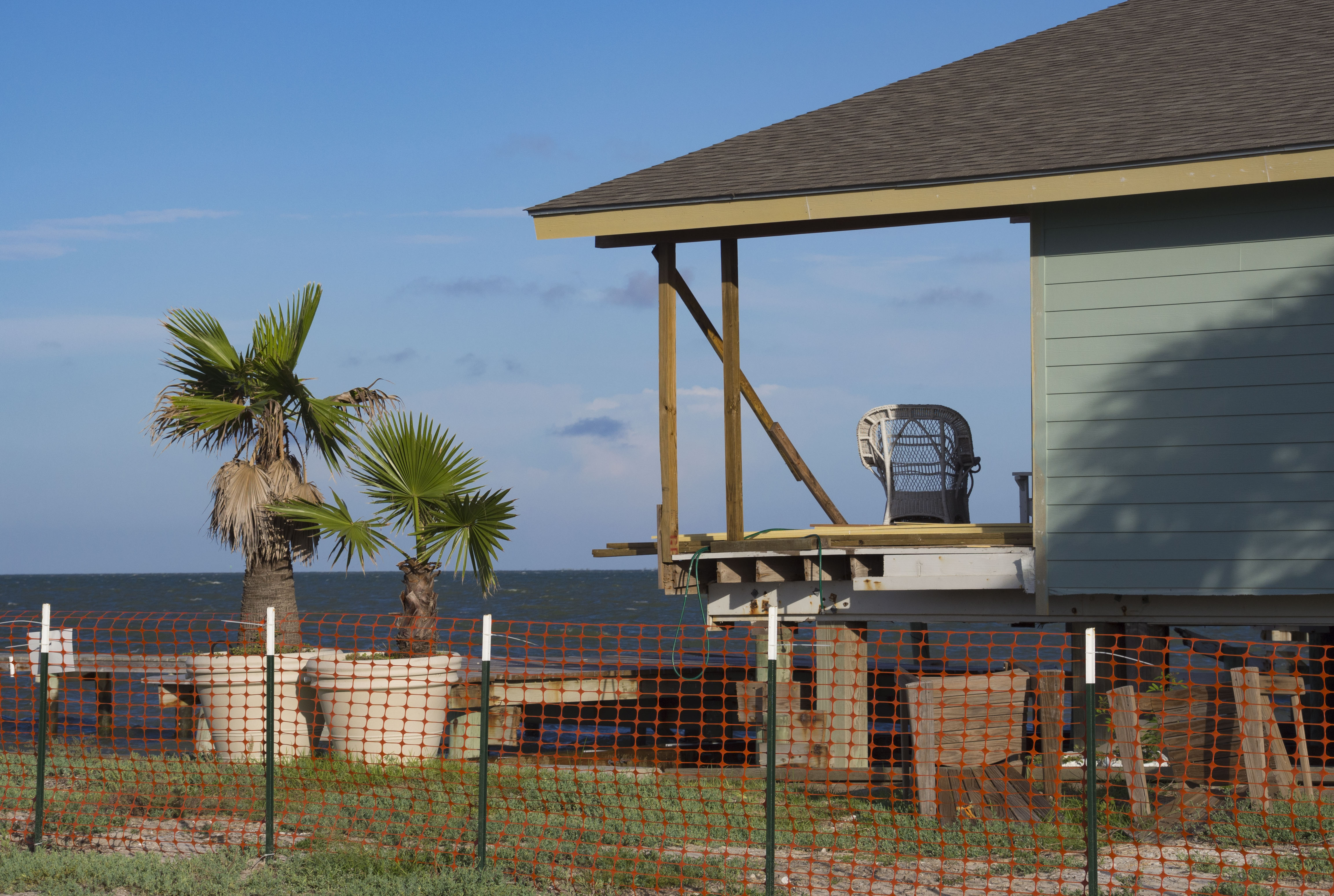 A solitary chair sits on a partially rebuilt deck facing a bay
