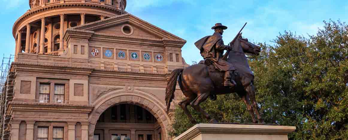 Texas Capitol building with statue of man on horse in foreground