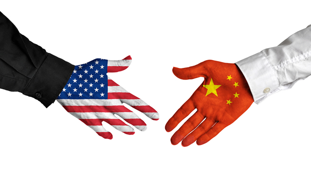 hands covered in Chinese and American flags shaking