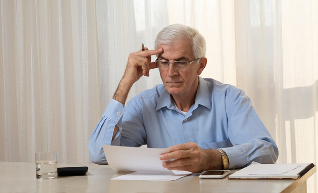 older man at desk concentrating on paperwork