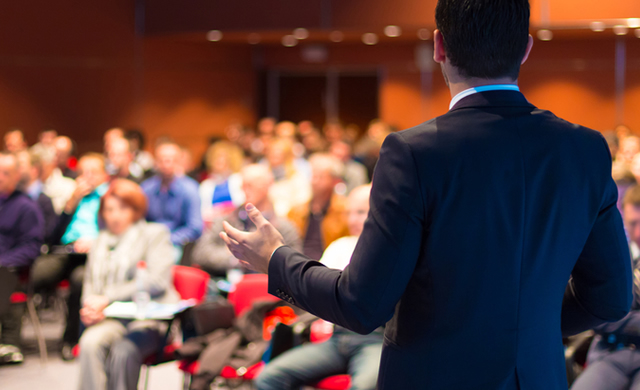 looking at audience and male speaker's back