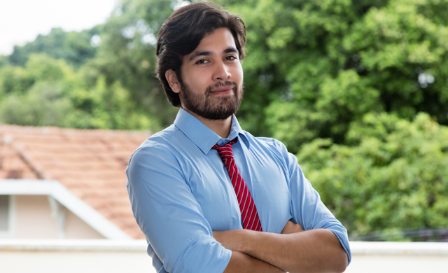 serious looking hispanic man in tie with arms crossed