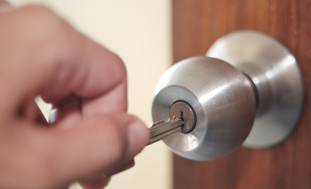 hand inserting key into door lock